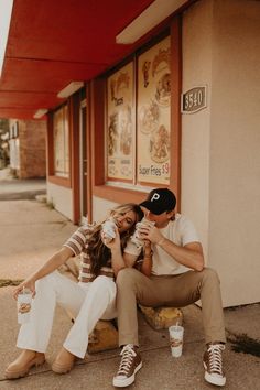 a man and woman sitting on a bench eating ice cream while holding cups in their hands