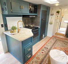 a kitchen with blue cabinets and an area rug on the floor in front of it