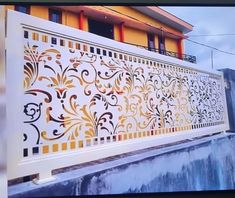 a white fence with gold designs on it and a building in the backround