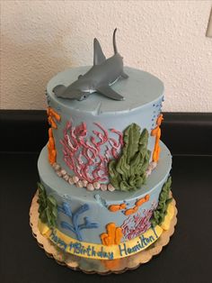 two tiered cake decorated with blue frosting and sea animals on the top layer