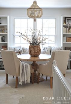 a dining room table with chairs and a basket on it's centerpiece in front of a window