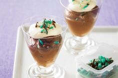 three desserts are sitting on a white tray with green decorations and frosting in them