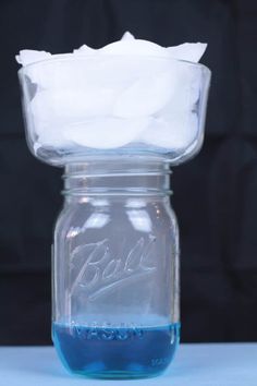 a glass jar filled with blue liquid sitting on top of a table