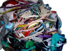 a large pile of different colored ribbons on top of each other in a white bowl