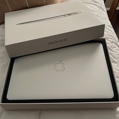 an apple macbook air box sitting on top of a bed with its lid open