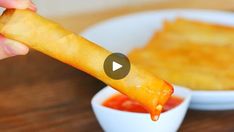 a person is dipping some food into a bowl with ketchup on the side