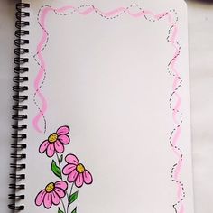 an open notebook with pink flowers on the cover and writing in black marker pen next to it