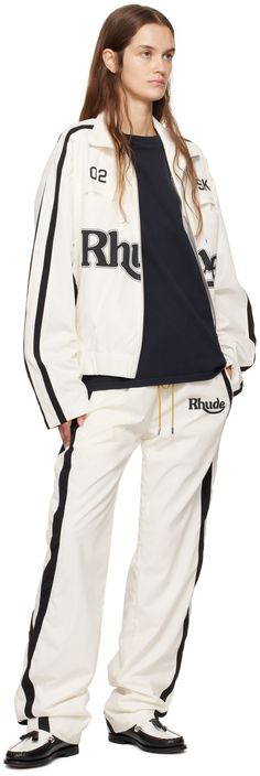 Polyester duck canvas track jacket. · Paneled construction · Funnel neck · Two-way zip closure · Text and logo printed at front · Welt and seam pockets · Elasticized hem · Dropped shoulders · Stripes at sleeves · Fully lined · Logo-engraved silver-tone hardware Supplier color: White/Black Fall Long Sleeve Track Jacket With Logo, Cotton Track Jacket With Logo Detail, Cotton Long Sleeve Track Jacket With Logo, Cotton Outerwear With Logo And Crew Neck, White Sporty Outerwear With Logo Detail, Sporty White Outerwear With Logo Detail, Long Sleeve Outerwear With Signature Stripes For Streetwear, Sporty College Outerwear With Logo Print, Cotton Track Jacket With Embroidered Logo For Fall