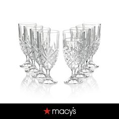 four crystal goblets sitting next to each other on top of a white surface