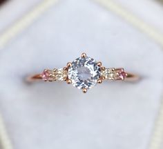 an engagement ring with three stones on the side and pink sapphires in the middle