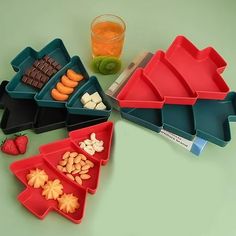 four trays with different foods and drinks on the counter top, including fruit, nuts, chocolate bars, and watermelon slices