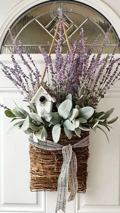 a basket filled with lavenders and greenery hangs on the front door's wall