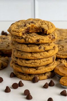 a stack of cookies with peanut butter and chocolate chips next to it on a white surface