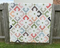 a quilt hanging on a fence in the grass