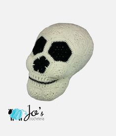 a white knitted skull with black dots on it's face and eyes, sitting in front of a white background