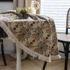 a table with a coffee cup on it and a flowered table cloth draped over it