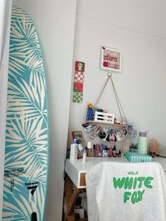 a surfboard is next to a white towel on a table in a room with other items