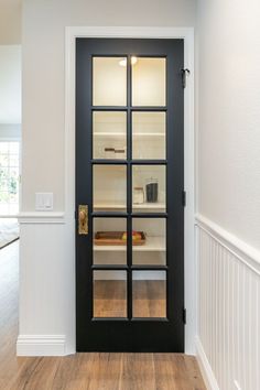 an empty room with a black door and white trim on the walls, along with hardwood floors