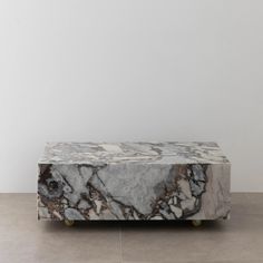 a marble bench sitting on top of a hard wood floor next to a white wall