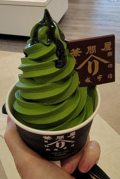 a person holding up a cup filled with green ice cream