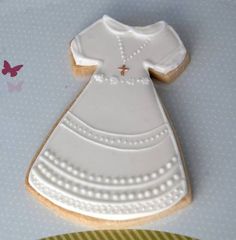 a cookie shaped like a baby's dress on top of a plate