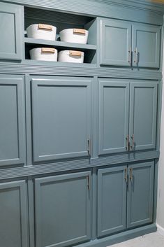 the cabinets are painted blue and have white baskets on them, along with other items