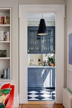 an open door leading to a kitchen with blue cabinets and white walls, along with bookshelves