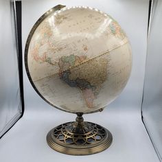 an old world globe is displayed in a glass case on a white surface with black trim