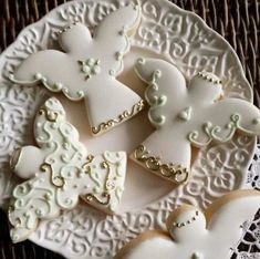 several decorated cookies on a white plate sitting on a lace doily tablecloth with an ornate design