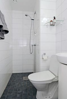 a white toilet sitting in a bathroom next to a walk in shower and tiled floor