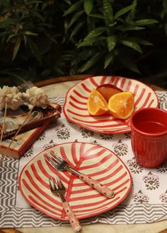 a table topped with plates and cups filled with food next to orange slices on top of each plate