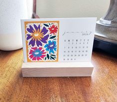 a desk calendar sitting on top of a wooden table