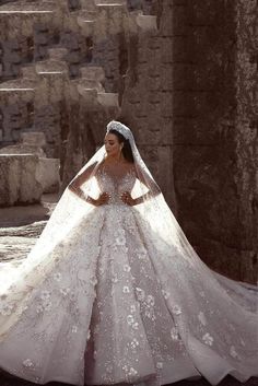 a woman in a wedding dress standing on some steps with her arms behind her back