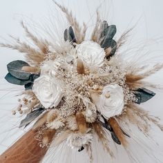 a bridal bouquet with white flowers and feathers