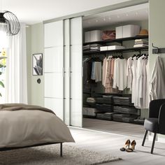 an open closet with clothes and shoes on the floor next to a bed in a bedroom