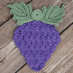 a crocheted purple and green hat laying on top of a wooden floor