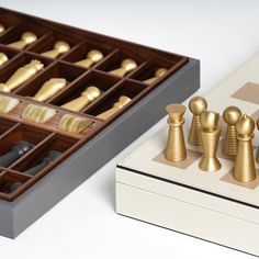 a wooden chess set sitting on top of a table next to a box with gold pieces in it