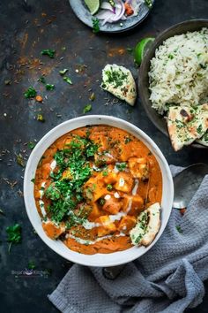 a bowl filled with curry and rice next to two bowls of food on a table