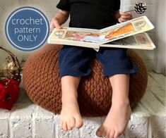 a little boy sitting on a bean bag reading a book