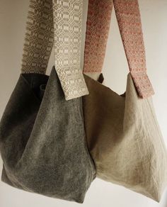 three purses hanging from the ceiling in front of a white wall with two different colored fabrics on them