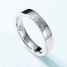 a white gold ring with a fingerprint on the front and center, set against a light blue background