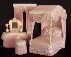 a dollhouse bedroom with pink furniture and curtains on the windowsill, including a canopy bed