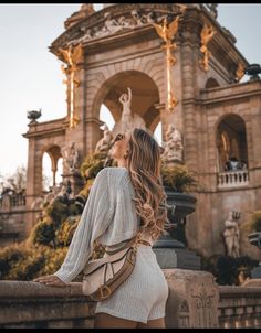 a woman standing in front of a fountain with her back to the camera and looking up