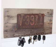 a wooden sign with keys hanging from it's hooks and the name v991 on it