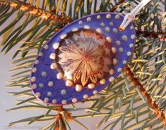 an ornament hanging from a pine tree with beads on it's sides