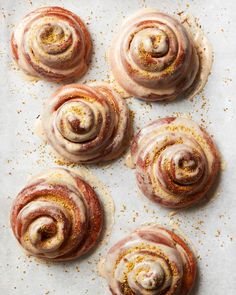 six cinnamon rolls on a baking sheet with sprinkles