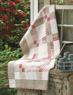 an old window sill with a quilt on top of it and flowers in the background