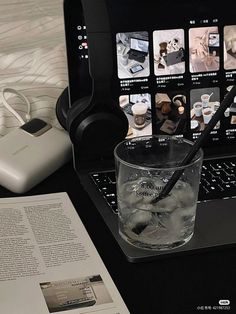 an open laptop computer sitting on top of a desk next to a glass filled with water