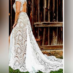 a woman in a white wedding dress standing next to a wooden door and looking at the ground