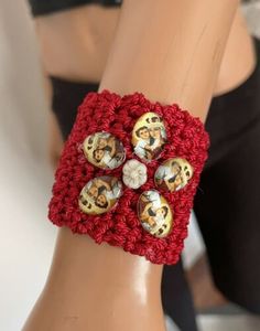 a close up of a person's arm wearing a red crochet bracelet